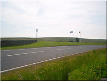 NT6906 : The A68 at Carter Bar with border flags, marker stone and beacon by Ann Clare