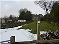 Footpath sign, stile, and remains of a snowdrift