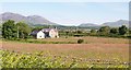 Tyddyn Perthi seen across a meadow from the A499