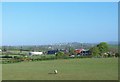 View across farmland to the buildings of a dairy farm