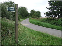 TL7354 : Footpath Sign And Country Road by Keith Evans