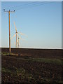 Electricity pole in field with wind farm behind