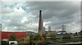 View of an old factory chimney and flats on Stratford High Street from the Lea Navigation
