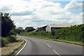 The B4011 passes barns near Leatherslade Farm