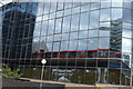 TQ3779 : View of a DLR train crossing the viaduct reflected in South Quay Plaza by Robert Lamb