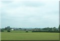 View across farmland towards a farmhouse and outbuildings on St James