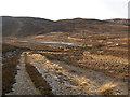 NH4535 : Moorland track, descending towards a lochan by Craig Wallace