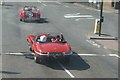 View of an E-Type Jaguar pulling away from the traffic lights at Eltham station from the top deck of a 132 bus on Well Hall Road