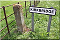 SE2590 : Guide post and village name sign in Kirkbridge by Roger Templeman