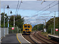 A yellow machine passing through Troon railway station