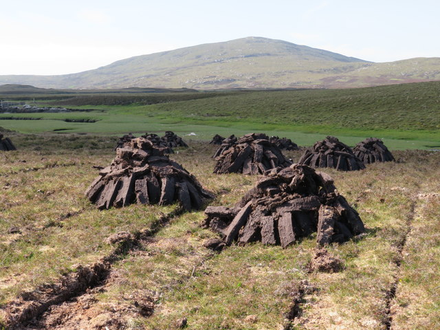 Peat stacks at Stolie Moorland dropping gently to a tidal channel, with Beinn Mhor in the distance.
