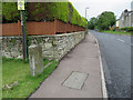 The B4226 Poolway Road and a defaced milestone