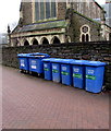 Blue wheelie bins alongside a churchyard perimeter wall, Neath