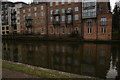 View of riverside flats reflected in the River Wensum from the towpath