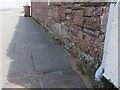 Sandstone wall with a bench mark in Meols Parade