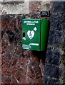 Green defibrillator box on a church wall, Murton