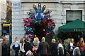 View of a peacock, flowers and lights at the entrance to The Ivy Market Grill