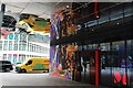 View of street art on the front of the Citizen M hotel and a DHL van reflected in the ceiling of the Citizen M hotel entrance