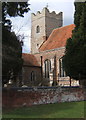 All Saints Church , Fordham, glimpsed from the road past the trees